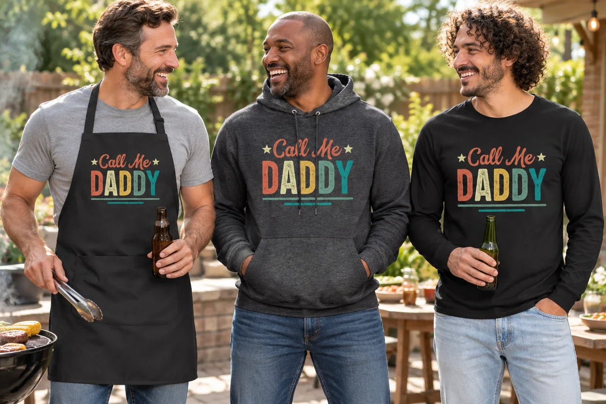 Three men wearing Call Me Daddy apparel with retro lettering on an apron, hoodie, and long-sleeve shirt at a backyard barbecue.