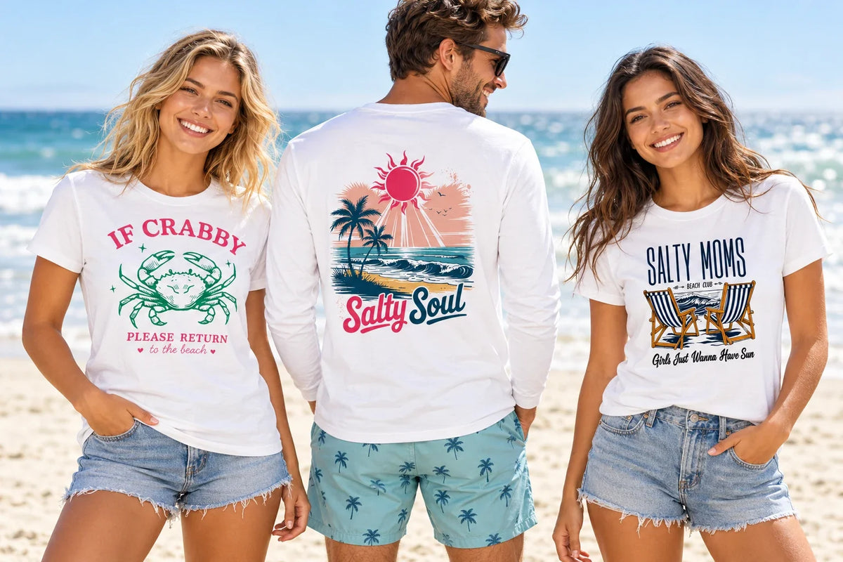 Three adults wearing Beach Vibes shirts with If Crabby, Salty Soul, and Salty Moms designs beside the ocean.