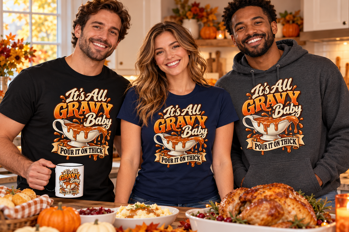 Friends wearing It’s All Gravy Baby Thanksgiving T-shirts and a hoodie with a matching gravy-boat coffee mug in an autumn kitchen.