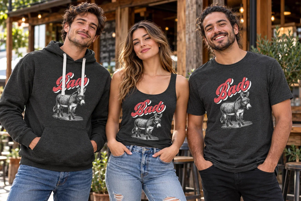 Three adults wearing Bad Ass donkey graphic apparel: a charcoal hoodie, a women’s tank top, and a T-shirt.