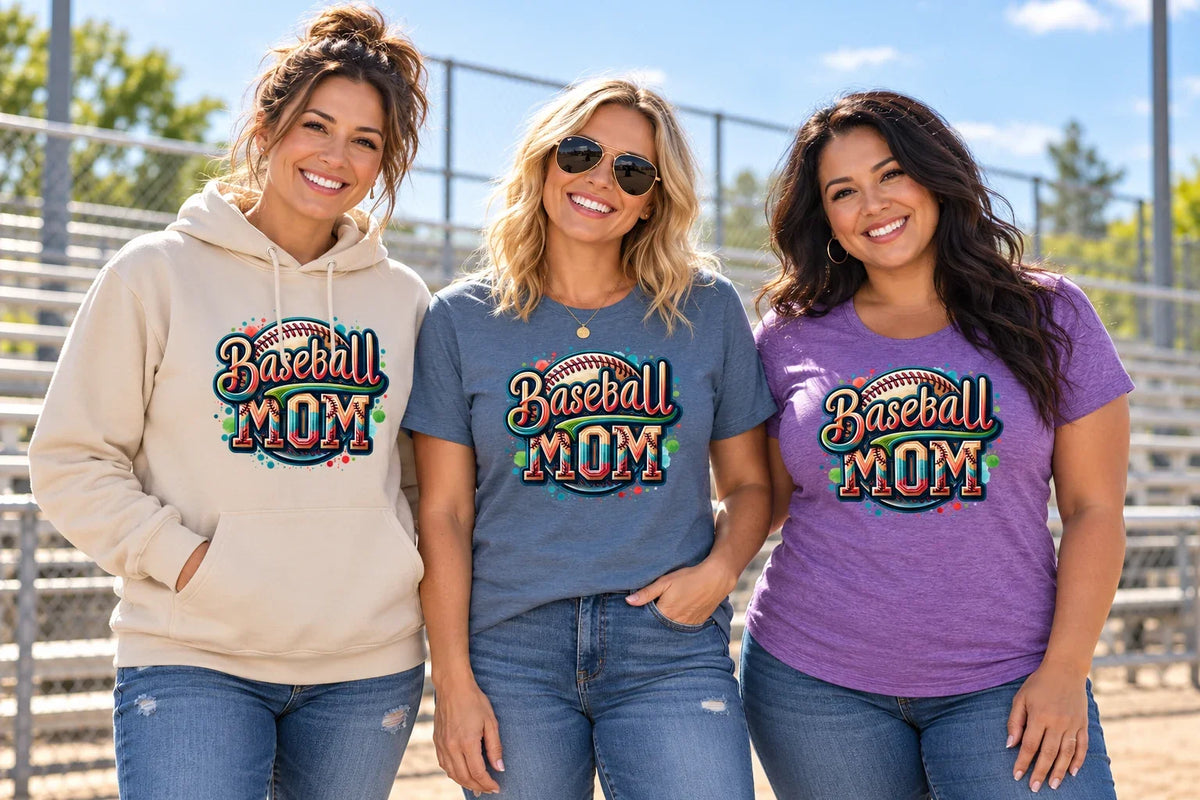 Three women wearing colorful Baseball Mom graphic shirts and a sand hoodie beside baseball bleachers.